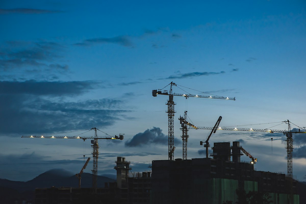 Tower cranes over an industrial construction site at dusk