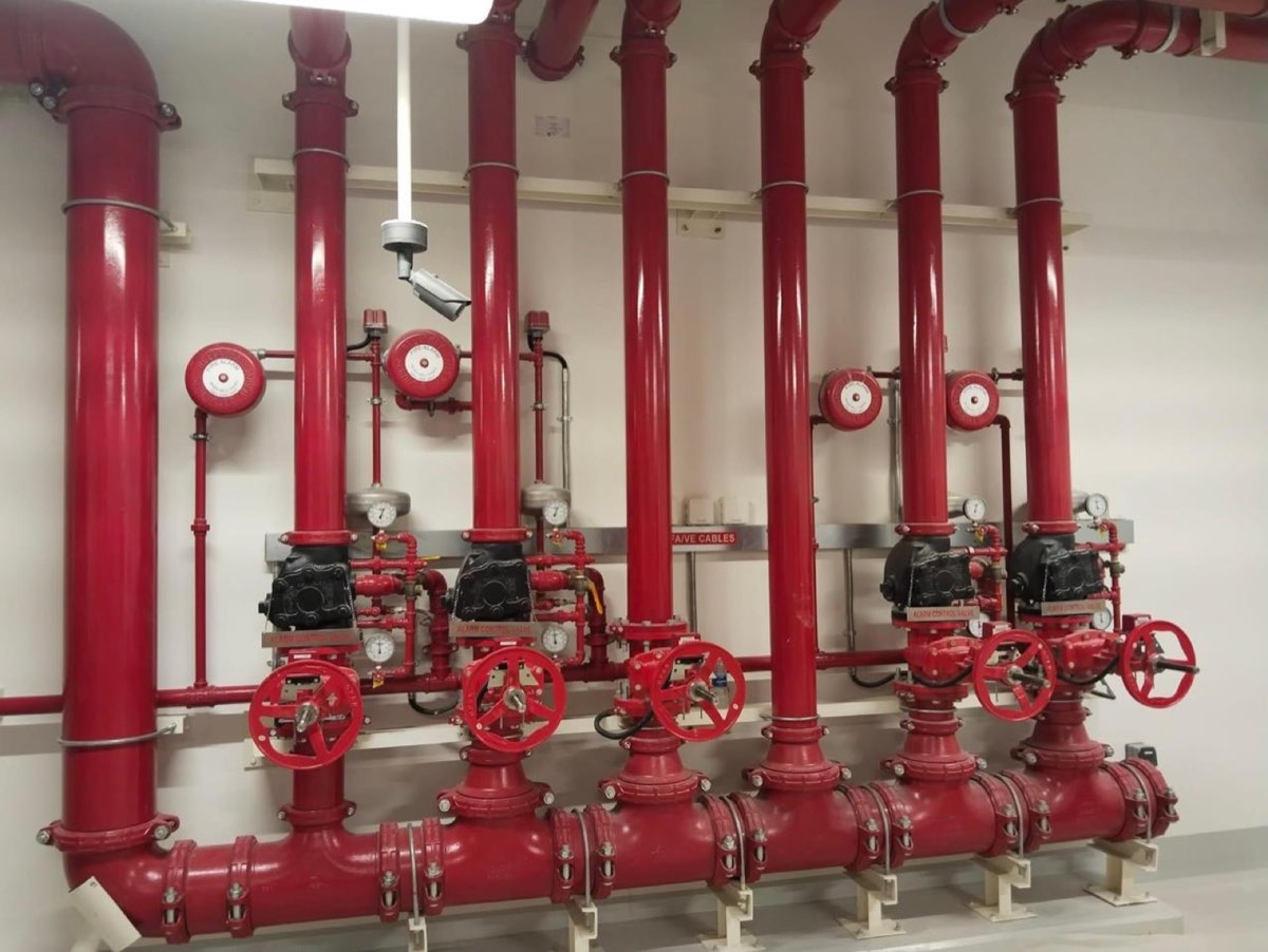 Fire fighting network with alarm control valves and red steel riser piping in a plant room
